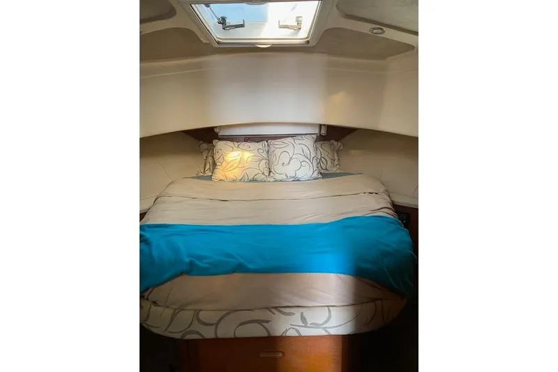 Slide: The Image of Cozy cabin interior of 1999 Mainship 350 Trawler with skylight and patterned bedding. - 29