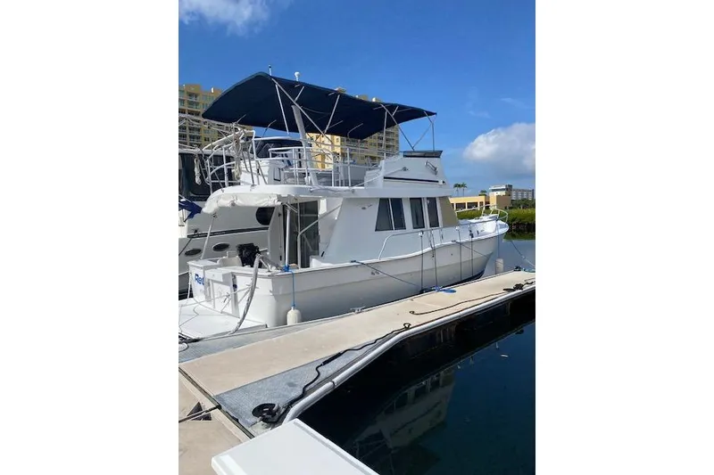 Slide: The Image of 1999 Mainship 350 Trawler docked, featuring a blue canopy and white exterior. - 3