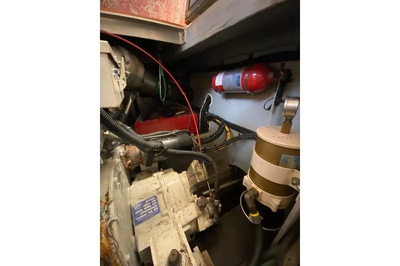 Slide: The Image of Engine room of 1999 Mainship 350 Trawler with fire extinguisher and mechanical components. - 32