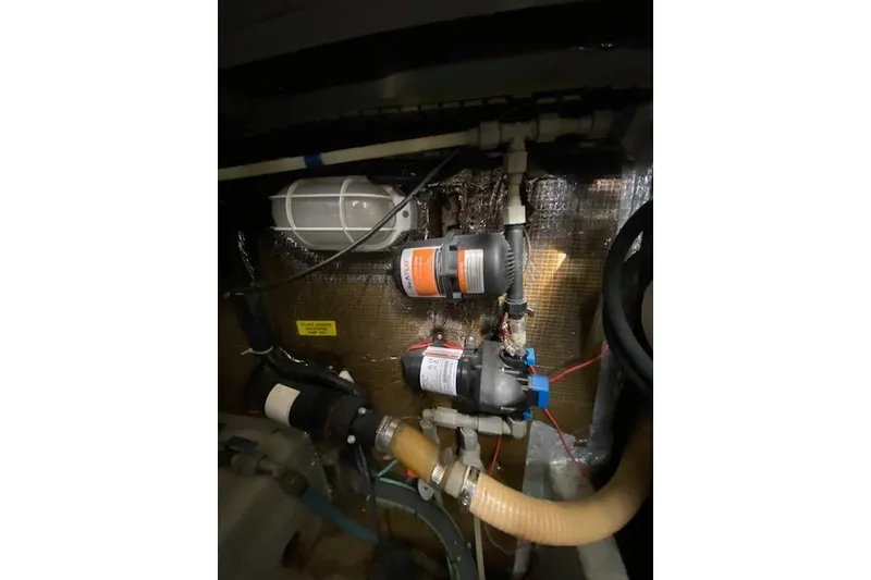 Slide: The Image of Engine room of a 1999 Mainship 350 Trawler, showcasing pumps and wiring. - 35