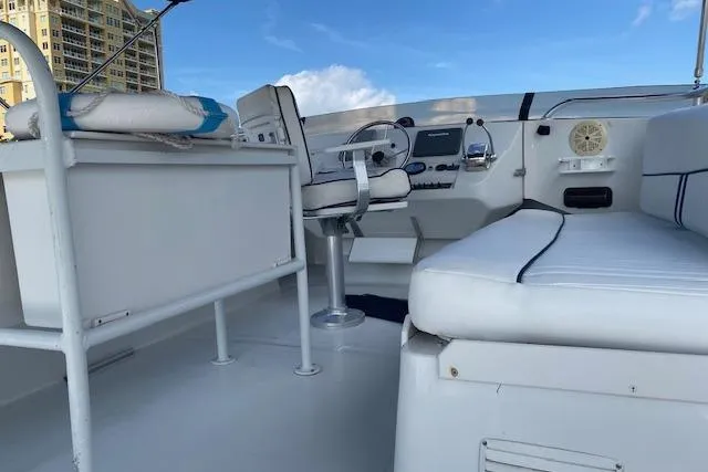 Slide: The Image of 1999 Mainship 350 Trawler cockpit with seating, steering wheel, and control panel under blue sky. - 4