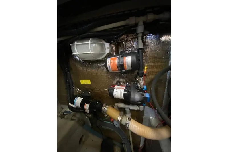 Slide: The Image of Engine room components of a 1999 Mainship 350 Trawler, featuring pumps and wiring. - 46