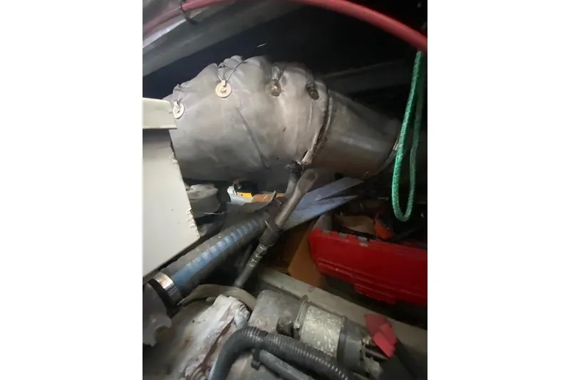 Slide: The Image of Engine room of a 1999 Mainship 350 Trawler, showing exhaust system and hoses. - 48