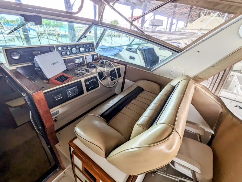 Slide: The Image of 1988 Sea Ray 390 Express Cruiser helm with leather seating and navigation equipment. - 13