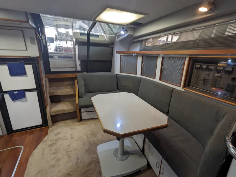 Slide: The Image of 1988 Sea Ray 390 Express Cruiser interior with gray seating and dining table. - 20