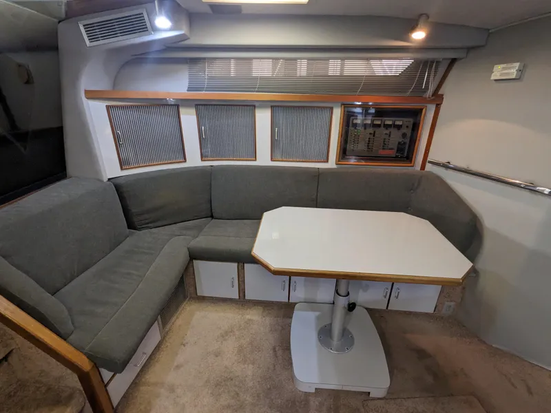Slide: The Image of 1988 Sea Ray 390 Express Cruiser interior with gray seating and dining table. - 23