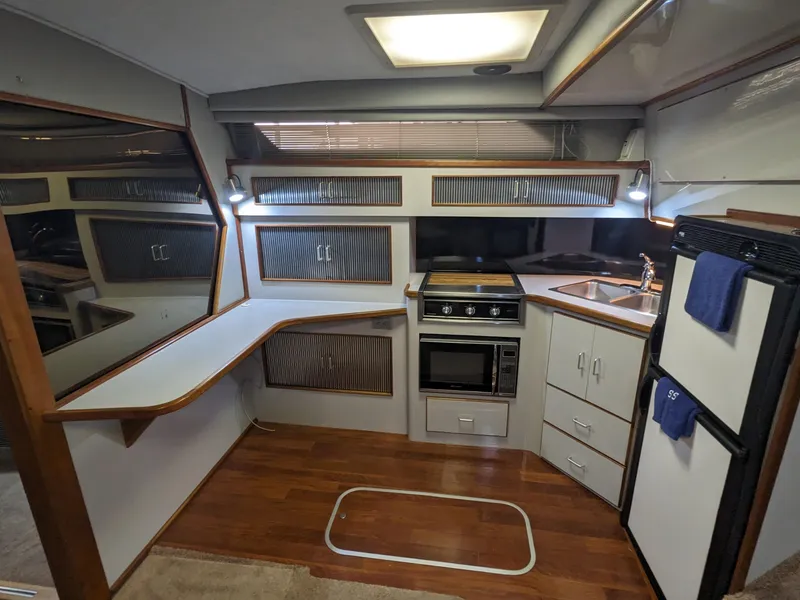 Slide: The Image of 1988 Sea Ray 390 Express Cruiser kitchen with wood flooring, stove, sink, and refrigerator. - 26