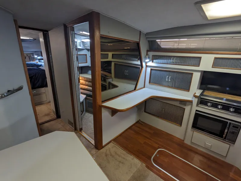 Slide: The Image of Interior of 1988 Sea Ray 390 Express Cruiser with kitchen and seating area. - 28