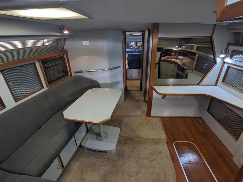 Slide: The Image of Interior of 1988 Sea Ray 390 Express Cruiser with seating, table, and kitchenette. - 29