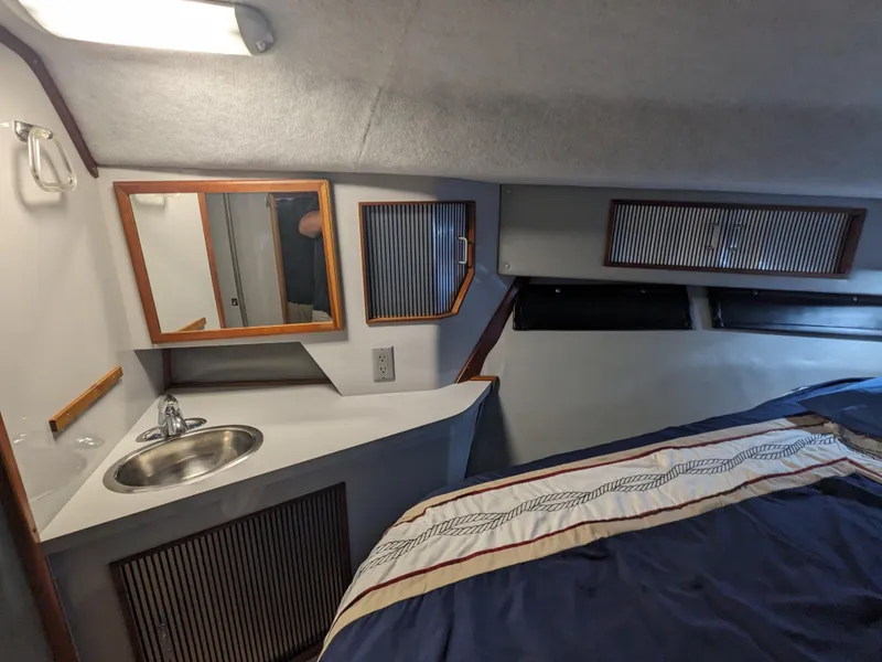 Slide: The Image of 1988 Sea Ray 390 Express Cruiser cabin with sink, mirror, and bed. - 32