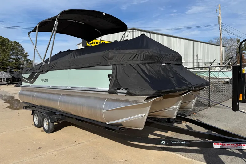 Slide: The Image of 2026 Avalon Venture 85 Versatile rear Bench pontoon boat on trailer, covered and parked outdoors. - 45