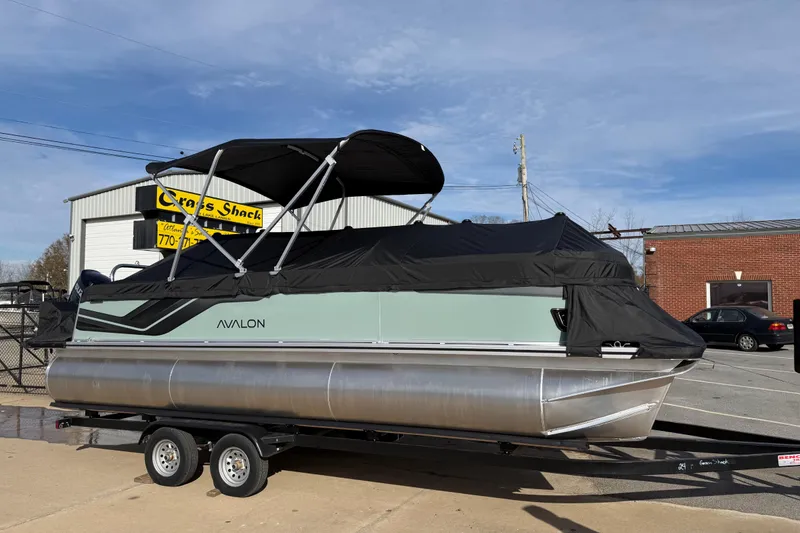 Slide: The Image of 2026 Avalon Venture 85 Versatile Rear Bench pontoon boat on trailer, covered and parked. - 46