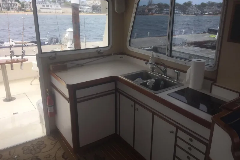 Slide: The Image of Interior of a 2001 Wesmac 38 boat featuring a compact kitchen area with sink and stove. - 12