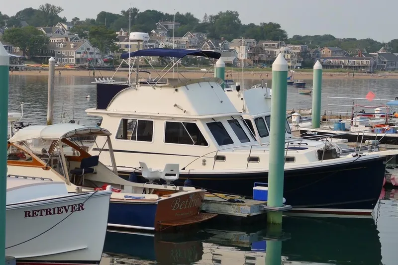 Slide: The Image of 2001 Wesmac 38 boat docked in a marina with coastal houses in the background. - 26