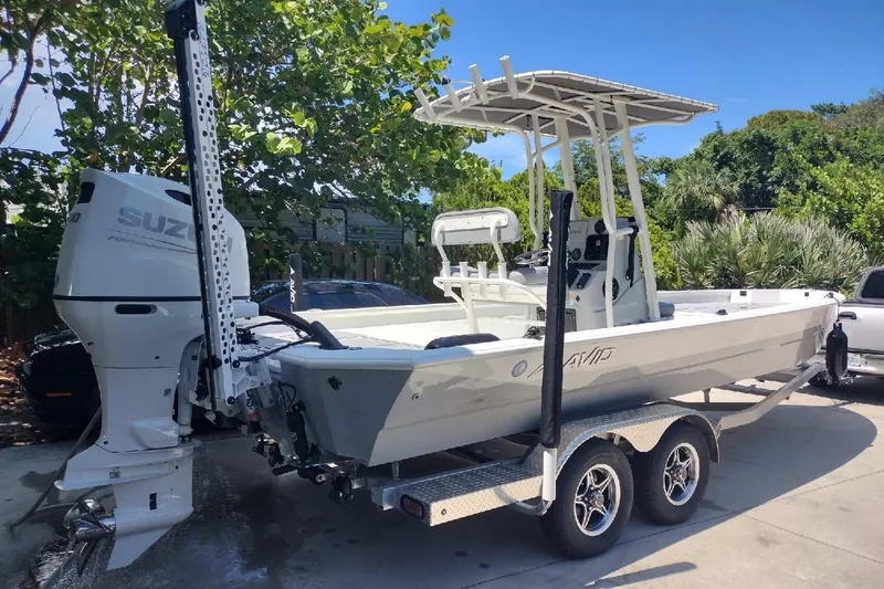 The Image of 2022 Avid 23 FS Magnum boat on trailer with Suzuki outboard motor, parked outdoors. - 1