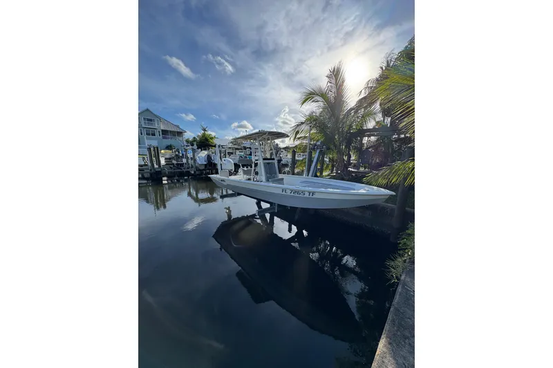 Slide: The Image of 2022 Avid 23 FS Magnum boat docked by palm trees under a sunny sky. - 3
