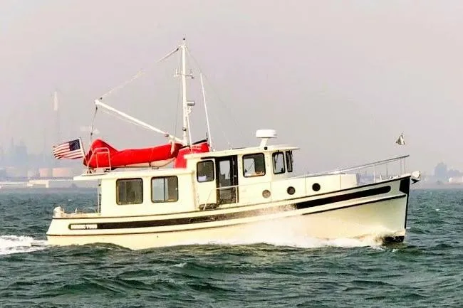 Slide: The Image of 2002 Nordic Tug 37 cruising on open water with American flag. - 2