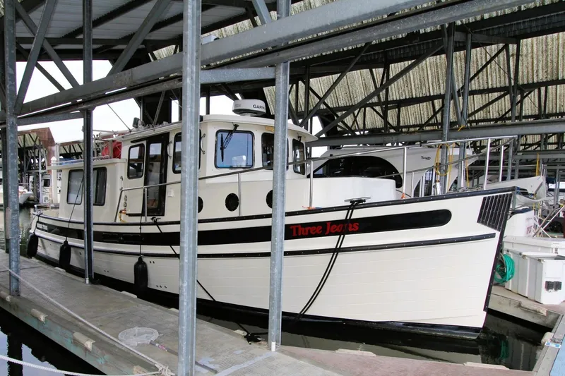 Slide: The Image of 2002 Nordic Tug 37 docked in a marina under a covered structure. - 5