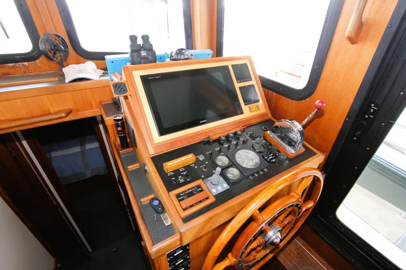 Slide: The Image of Nordic Tug 37 (2002) helm with wooden wheel, navigation controls, and display screen. - 8