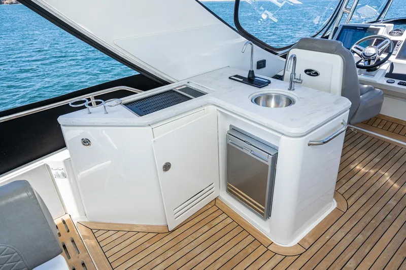 Slide: The Image of 2018 Sea Ray L590 Fly yacht kitchen with sink, mini-fridge, and wooden flooring. - 17