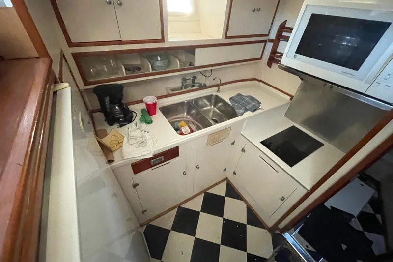 Slide: The Image of 1958 Huckins Seafarer kitchen with checkered floor, sink, microwave, and coffee maker. - 13
