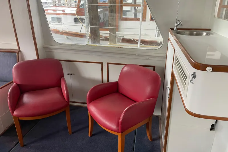Slide: The Image of Interior of a 1958 Huckins Seafarer with red chairs and a small sink. - 15