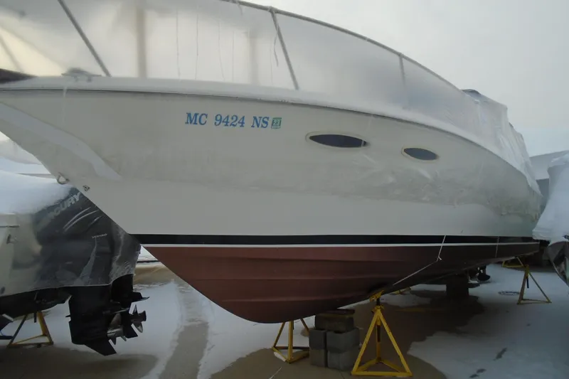 The Image of 1989 Sea Ray 300 Weekender boat on stands, partially covered, with visible registration number. - 0