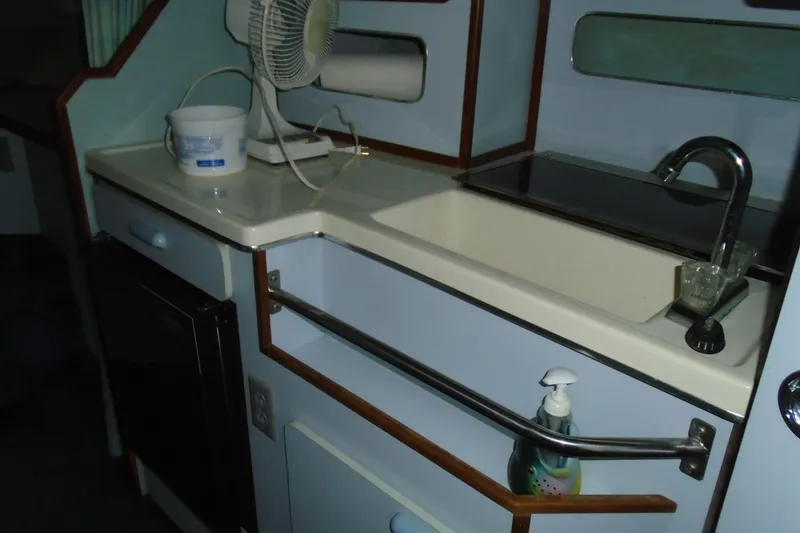 Slide: The Image of 1989 Sea Ray 300 Weekender interior with sink, fan, and storage. - 18