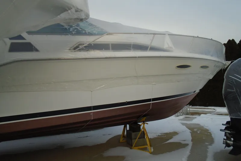 Slide: The Image of 1989 Sea Ray 300 Weekender boat, winterized and covered, on stands in a snowy setting. - 4