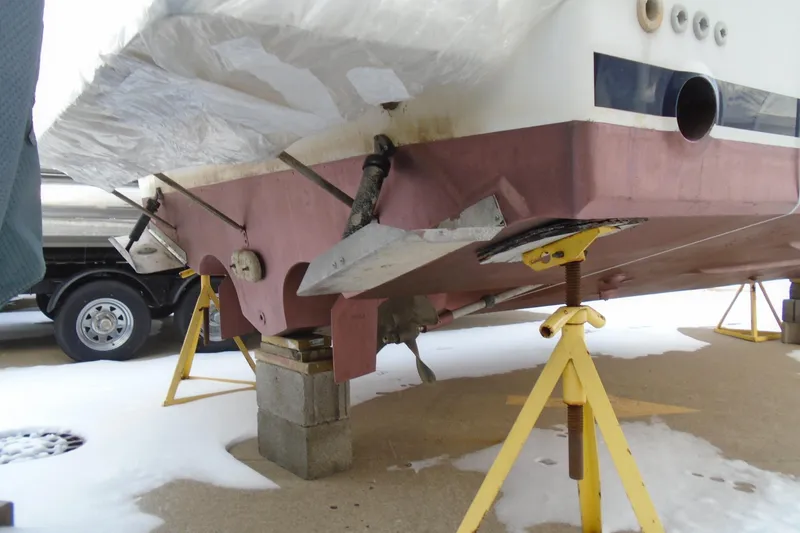 Slide: The Image of 1989 Sea Ray 300 Weekender on stands, showing hull and propeller area in winter storage. - 6