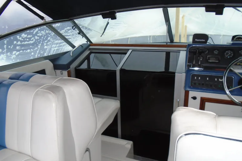 Slide: The Image of 1989 Sea Ray 300 Weekender boat interior with white and blue seating, dashboard, and steering wheel. - 8
