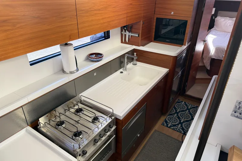Slide: The Image of Modern kitchen interior in 2020 Amel 50 yacht with stove, sink, and wooden cabinetry. - 21