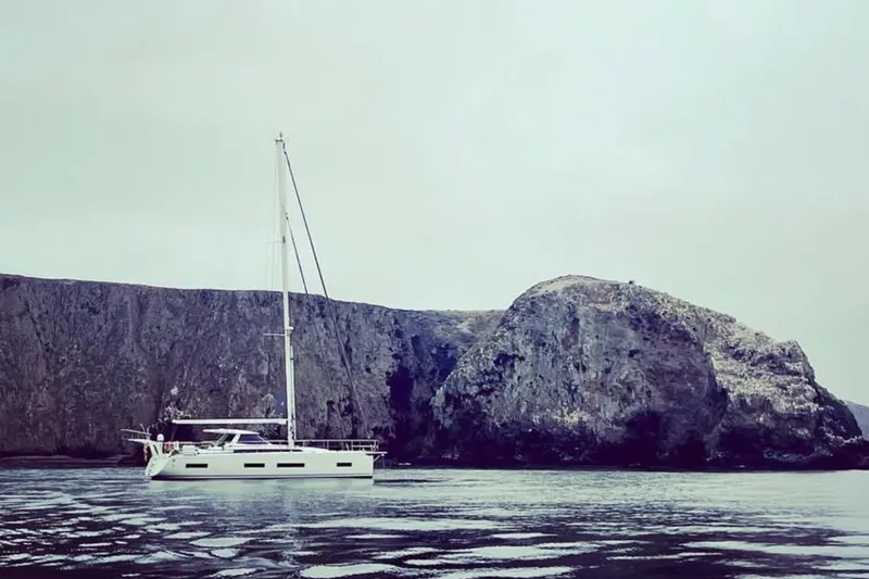 Slide: The Image of Sailing yacht Amel 50, 2020 model, near rocky coastline under overcast sky. - 51