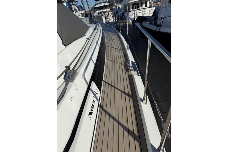 Slide: The Image of Side deck of 2020 Amel 50 yacht in marina, featuring sleek design and railing. - 62