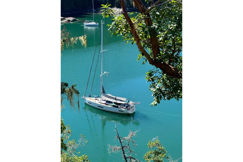Slide: The Image of Sailboat Amel 50, 2020 model, anchored in serene turquoise waters surrounded by lush greenery. - 70