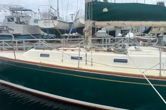 The Image of 1977 Tartan 37 sailboat with green hull docked at marina. - 0