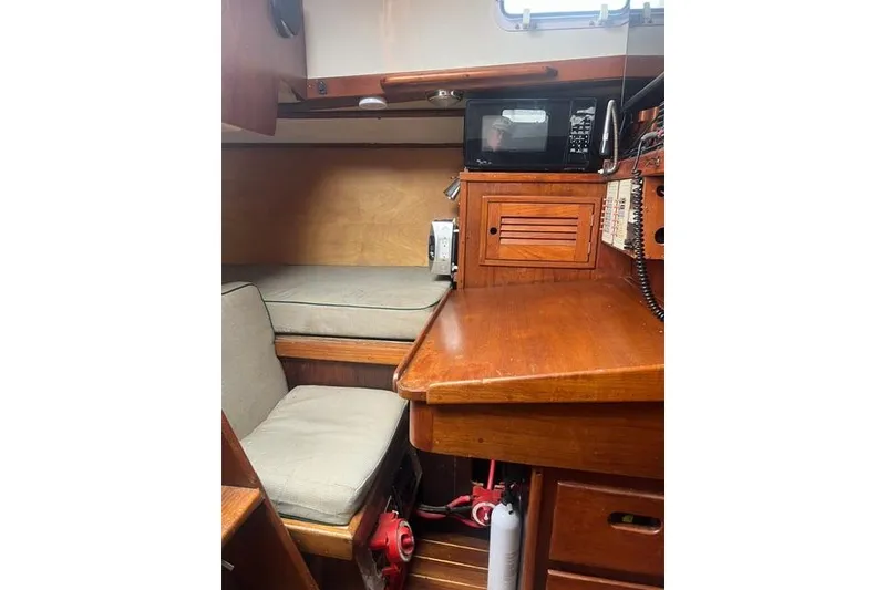 Slide: The Image of 1977 Tartan 37 sailboat interior with wooden desk, seating, and microwave. - 5
