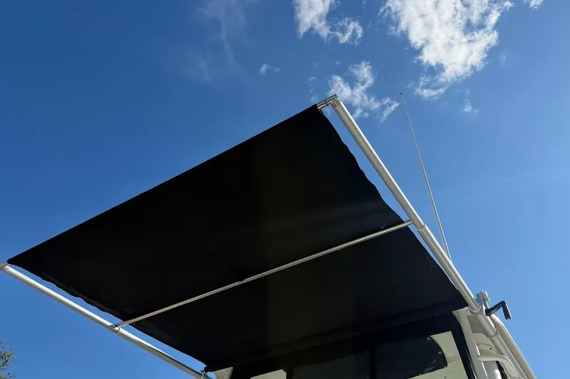 Slide: The Image of 2017 Boston Whaler 285 Conquest boat with extended black canopy under blue sky. - 21