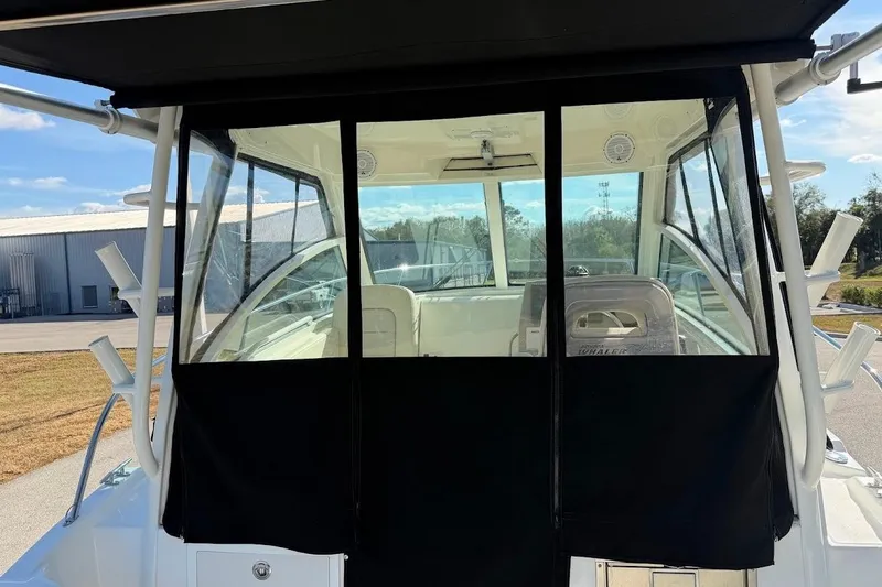 Slide: The Image of 2017 Boston Whaler 285 Conquest boat with black canvas enclosure, docked outdoors. - 24