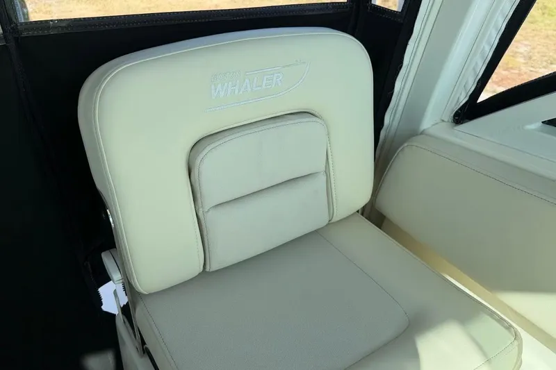 Slide: The Image of 2017 Boston Whaler 285 Conquest seat with logo, featuring beige upholstery. - 28