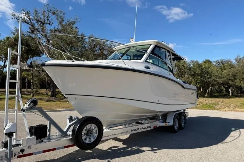 Slide: The Image of 2017 Boston Whaler 285 Conquest boat on trailer, parked outdoors under blue sky. - 4