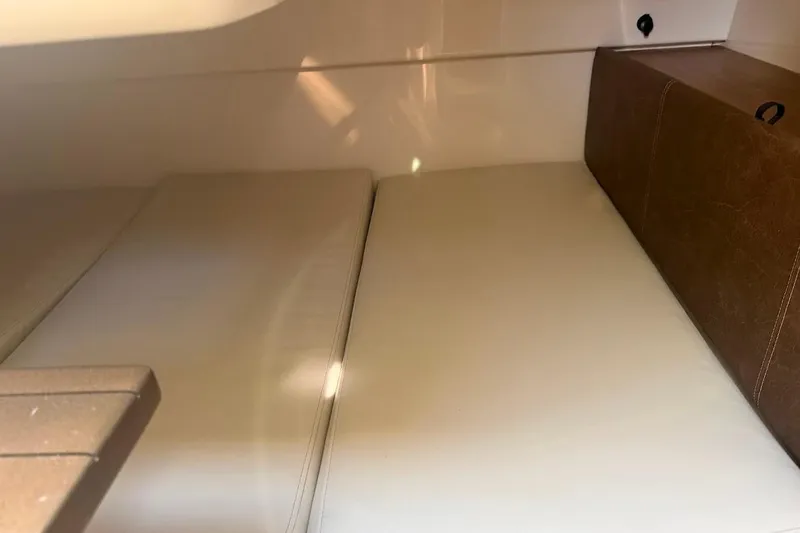 Slide: The Image of 2017 Boston Whaler 285 Conquest cabin interior with beige cushions and brown accents. - 43