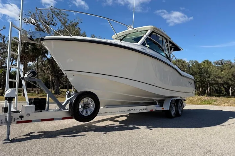 Slide: The Image of 2017 Boston Whaler 285 Conquest boat on trailer, parked outdoors under blue sky. - 5