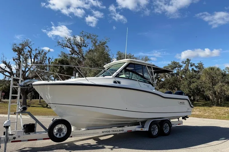 Slide: The Image of 2017 Boston Whaler 285 Conquest boat on trailer, parked outdoors under blue sky. - 6