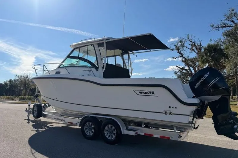 Slide: The Image of 2017 Boston Whaler 285 Conquest boat on trailer, parked outdoors under clear sky. - 8