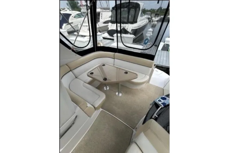 Slide: The Image of 2007 Four Winns 338 Vista boat interior with beige seating and triangular table. - 8