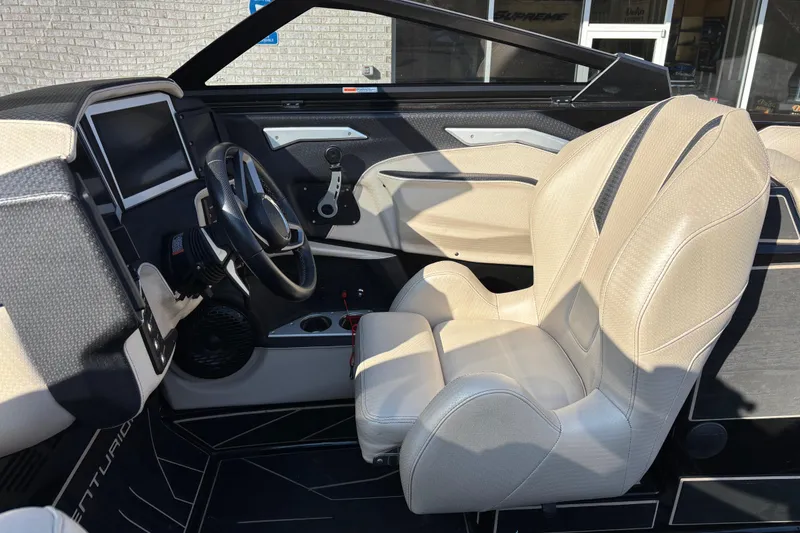 Slide: The Image of 2022 Centurion Ri265 boat interior with beige seating and modern dashboard. - 10