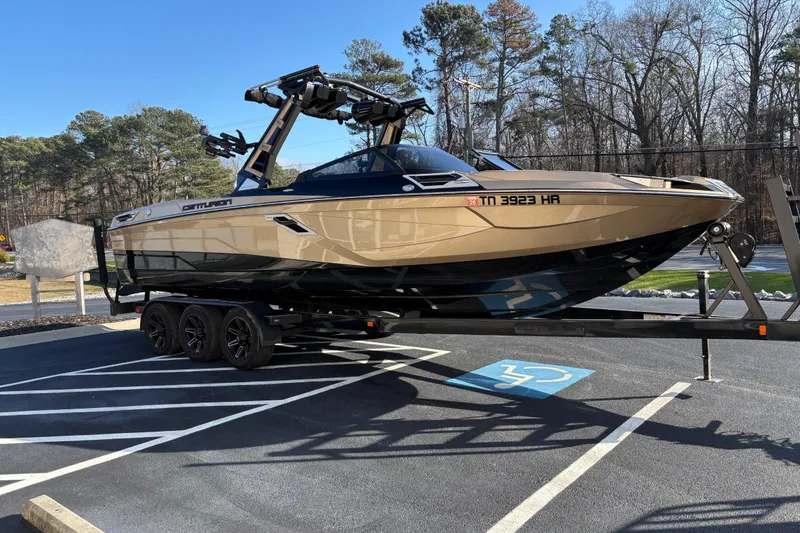Slide: The Image of 2022 Centurion Ri265 boat on trailer in parking lot, surrounded by trees. - 3