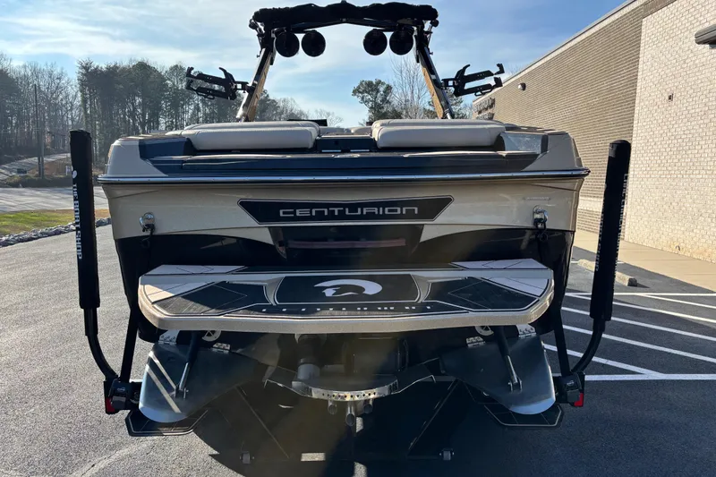Slide: The Image of 2022 Centurion Ri265 boat rear view in parking lot, showcasing sleek design and features. - 4