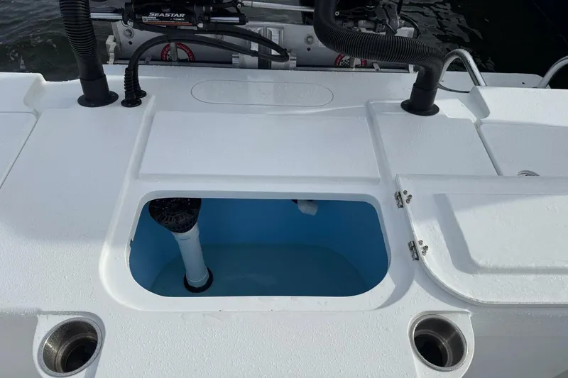Slide: The Image of 2023 T Craft 27 boat deck with open storage compartment and visible plumbing. - 12
